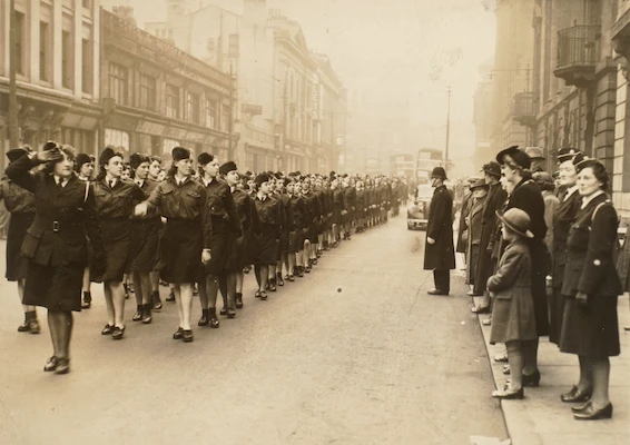 Vintage photograph of a wartime or post-war parade of uniformed women marching through a Preston street.