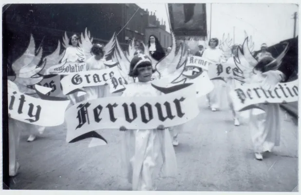 Historic black-and-white photo of a St Walburge's procession with children dressed as angels, led by a child carrying a "Fervour" banner.
