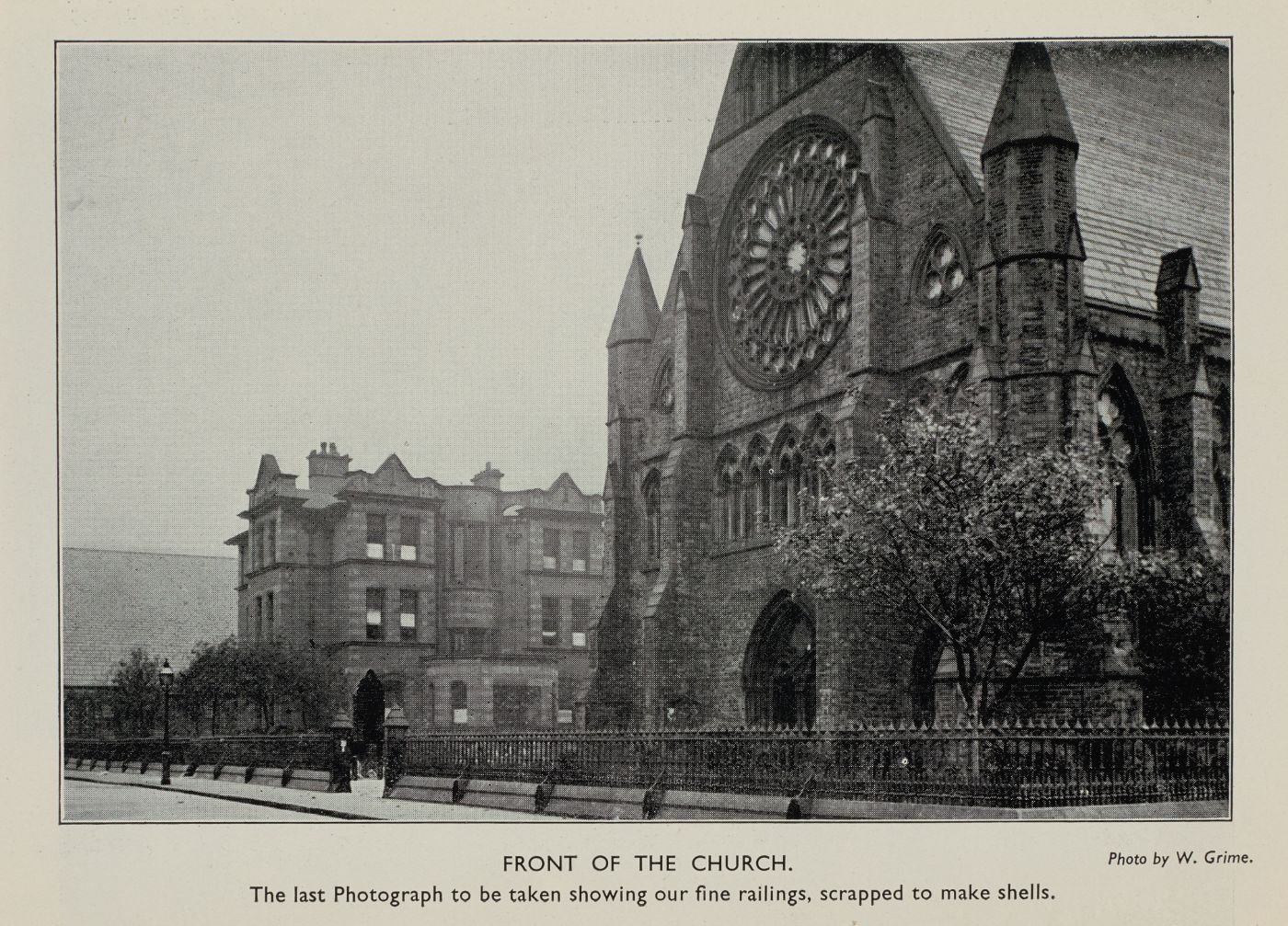 Photograph of St Walburge's west front and rose window with its original iron railings, captioned "Front of the Church. The last photograph to be taken showing our fine railings, scrapped to make shells." Photo by W. Grime.