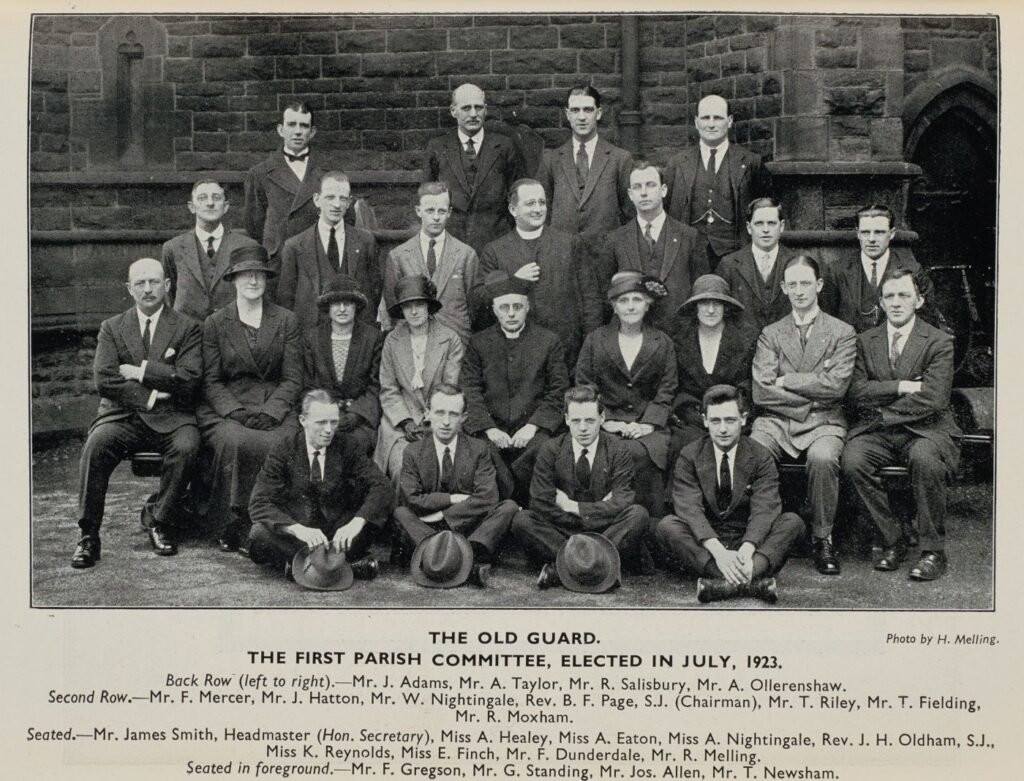 Group photograph of the first parish committee, elected July 1923, arranged in four rows outside the church, each member named in the printed caption below.