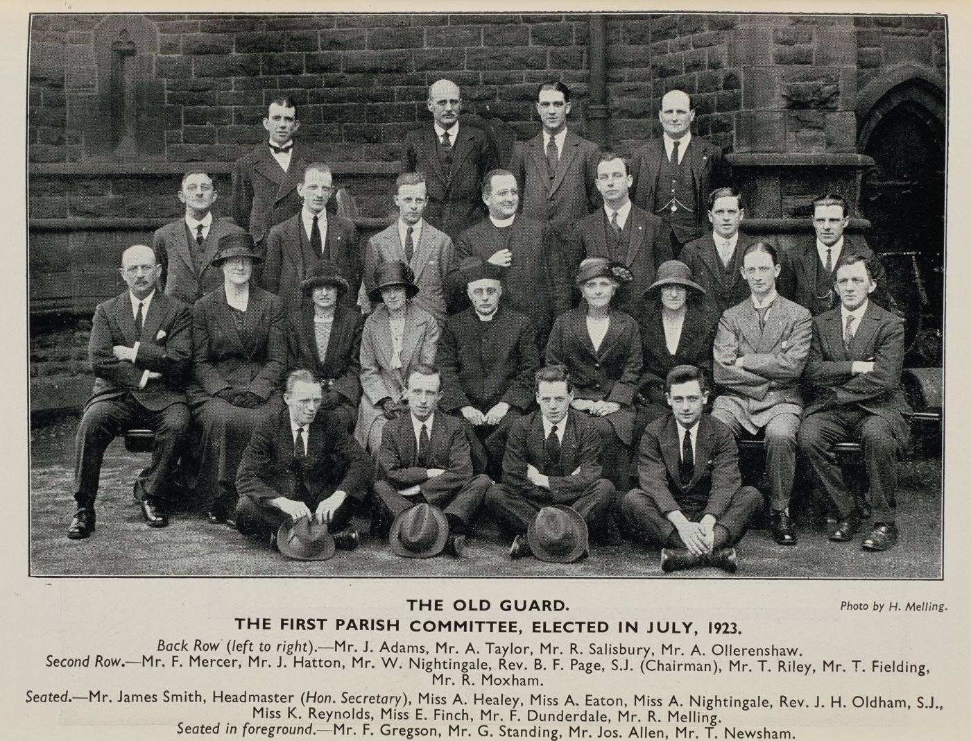 Group photograph of the first parish committee, elected July 1923, arranged in four rows outside the church, each member named in the printed caption below.