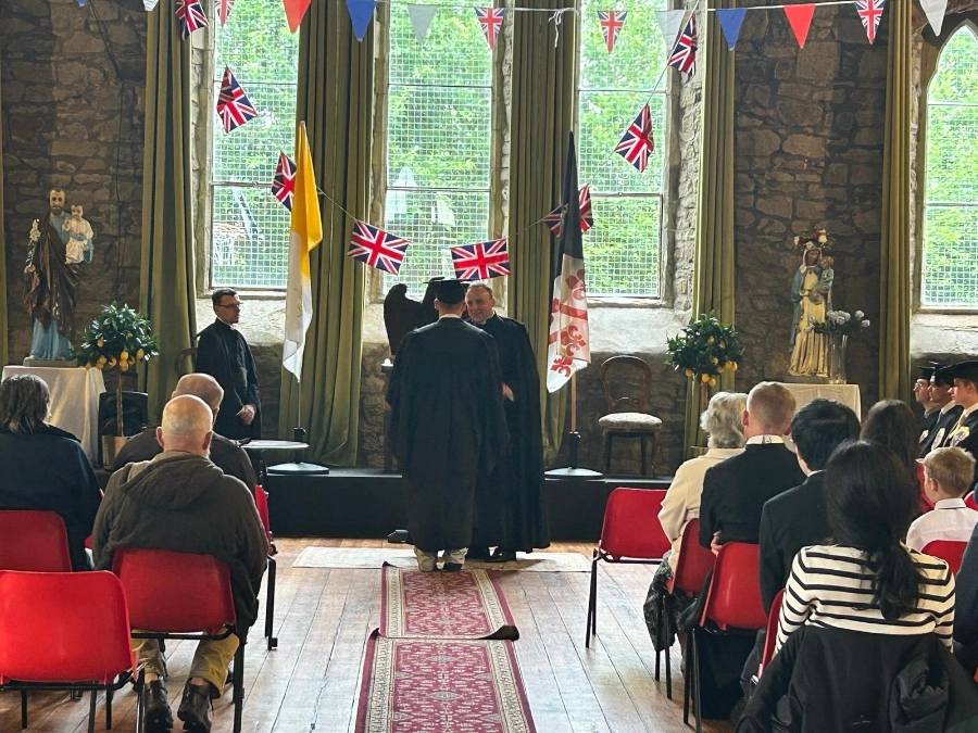 A ceremony at the front of the hall at St Walburge's, watched by a seated audience beneath Union Flag bunting.