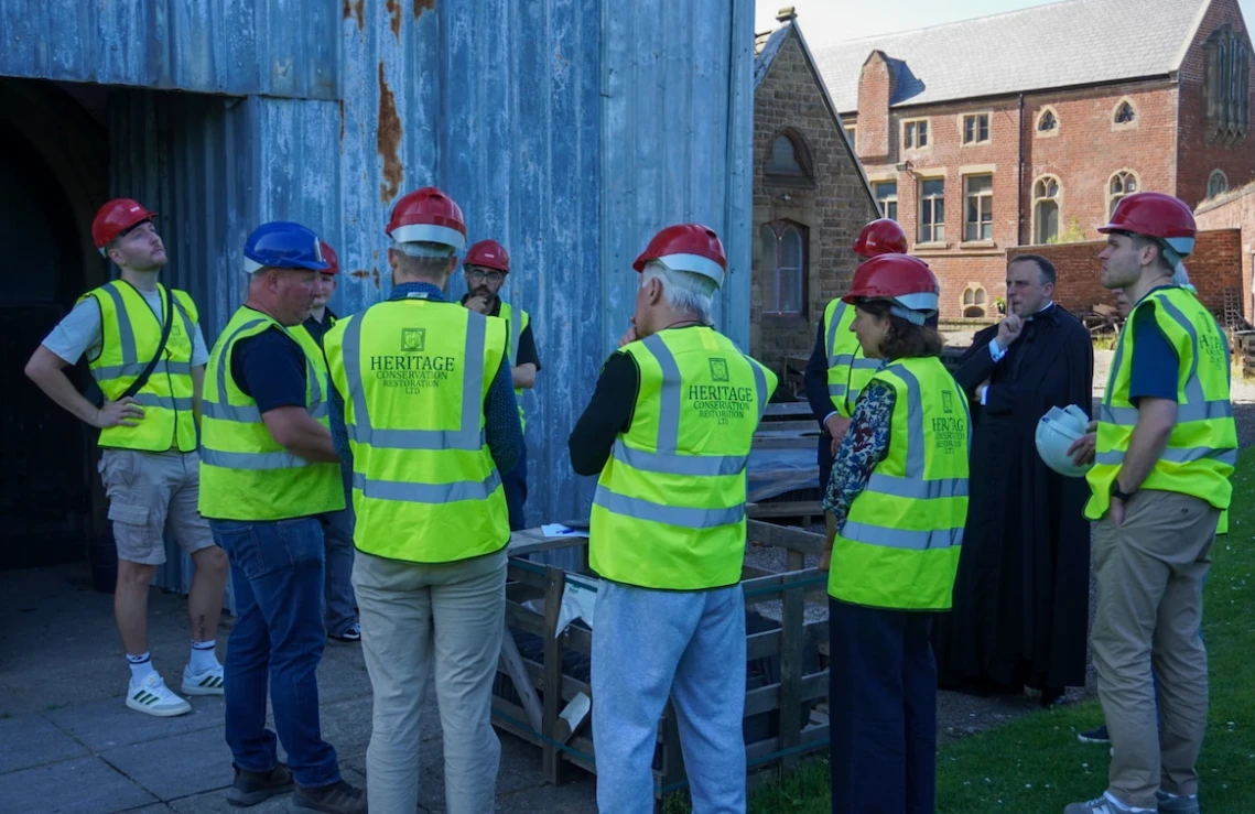 Visitors in hard hats and high-visibility vests gather for a tour of the restoration works at St Walburge's.